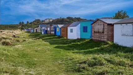 Fototapeta na wymiar Hopemans' Iconic beach huts with a cloudy blue sky in the background, Moray, Scotland