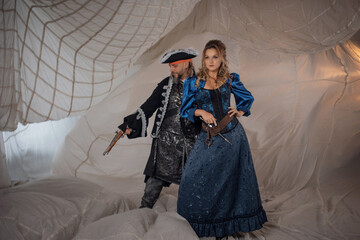 A lady and a pirate in an antique doublet and hat, a couple in pirate costumes. sails on the...