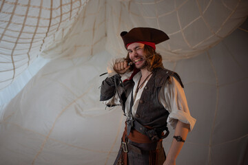 A cheerful and funny pirate in a cocked hat, a guy in a pirate costume with a gun, a sea robber, a...
