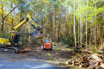 In preparation for constructing new home builder uproots trees from forest uses tractor