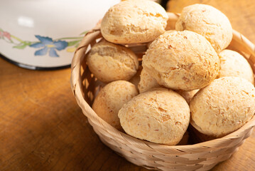 Cheese bread, basket with cheese bread arranged on rustic wood, dark background, selective focus.