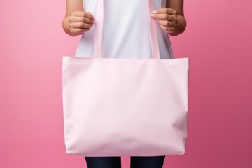 woman on mid frame holding a pale pink tote bag, sharply contrasted against a soft pink background, suggesting a minimalist fashion theme