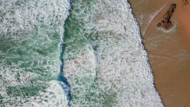 Lift d rone flying high above the shore with blue waves of amazing beauty and sandy shore