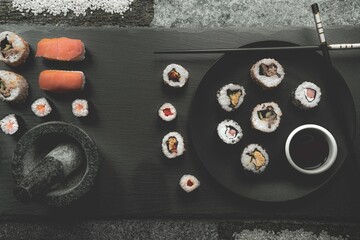 Top view of sushi rolls and nigiri on the black wooden board © Wirestock