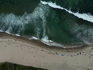 Aerial shot of the beach with the waves of water crashing on the shore, Los angeles, Malibu © Wirestock