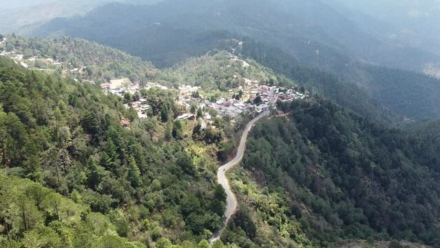 Aerial Take from over the forest trees to a town in the mountains.