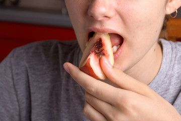 female hand putting a piece of ripe peach in the mouth, healthy food dessert, food lifestyle. Woman...