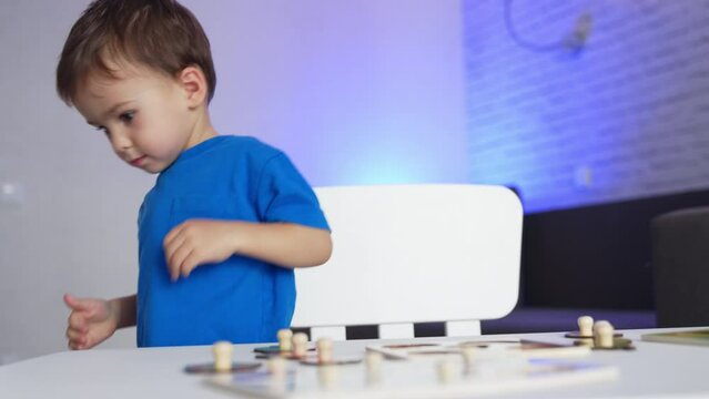 Caucasian baby boy playing with his toys at desk. Kid finishes a game and stands up and leaves.