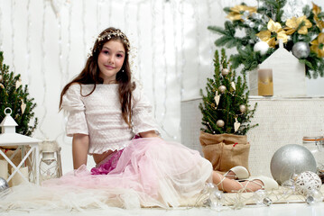 A teenage girl in a delicate fairy-tale princess costume lies comfortably on a woolen carpet,...