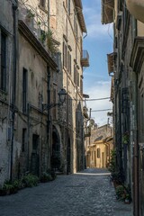 Obraz premium Vertical shot of a narrow paved street passing through old medieval residential buildings in Italy