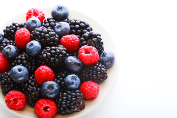 Raspberries, blackberries and blueberries in white bowl.