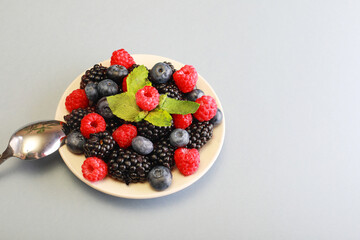 Raspberries, blackberries and blueberries in white bowl.