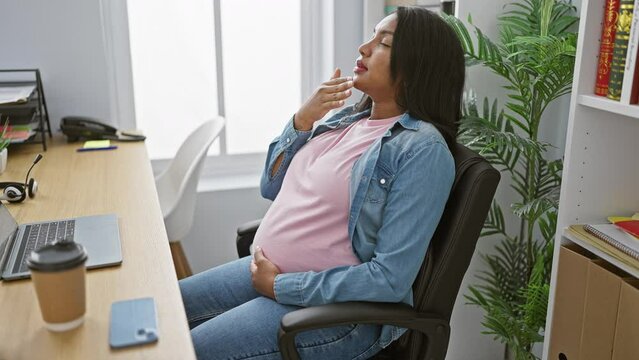 Serious young pregnant businesswoman touching belly, suffering nausea indoors at office