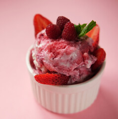 Bowl of pink strawberry ice cream and fresh berries