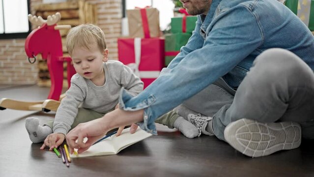 Father and son celebrating christmas drawing on notebook at home