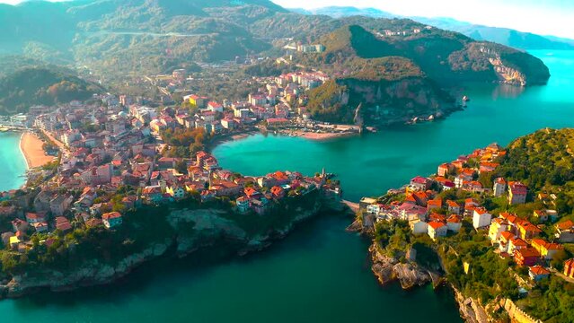 City view in the Amasra mountains. The drone is slowly approaching the beautiful landscape. Aerial view of houses and deep blue sea. Amasra, Turkey.