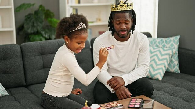 African american father and daughter wearing king crown playing with makeup at home