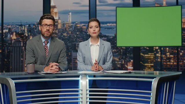 Serious presenters talking greenscreen news standing evening tv studio closeup