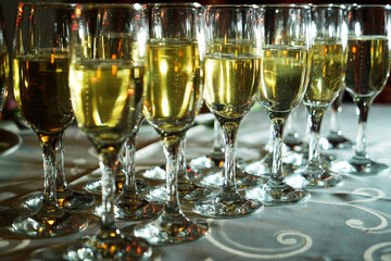 a stylishly set table with a glass of champagne. A charming glass filled with sparkling drink shines in the light. The table is covered with an elegant tablecloth