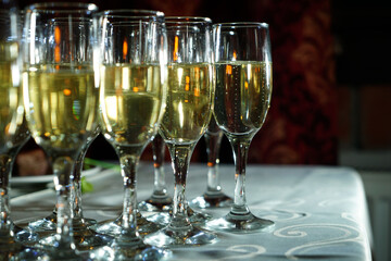 a stylishly set table with a glass of champagne. A charming glass filled with sparkling drink shines in the light. The table is covered with an elegant tablecloth