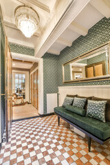 a living room with green and white wallpapered walls, an ornate mirror above the couch is on the...