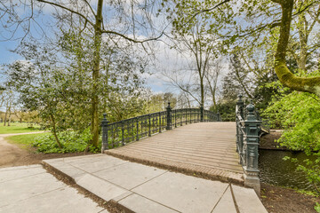 a bridge in the middle of a park with some trees and bushes on either side of the path that leads up to it