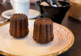 Canele, French pastry flavored with rum and vanilla, specialty of Bordeaux region, France, served with cup of black coffie in French restaurant