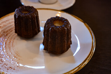 Canele, French pastry flavored with rum and vanilla, specialty of Bordeaux region, France, served with cup of black coffie in French restaurant