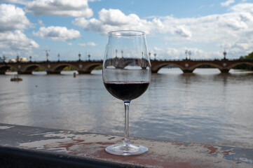 Tasting of Bordeaux blended red wine with wine city Bordeaux on background, left bank of Gironde Estuary, France. Glass of red French wine.