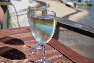 Drinking of white wine at farm cafe in oyster-farming village, with view on boats and water of...