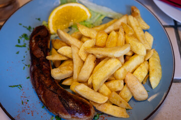 Fried fries potatoes with grilled meat German sausage served in old restaurant in Germany