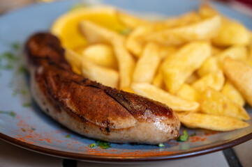 Fried fries potatoes with grilled meat German sausage served in old restaurant in Germany