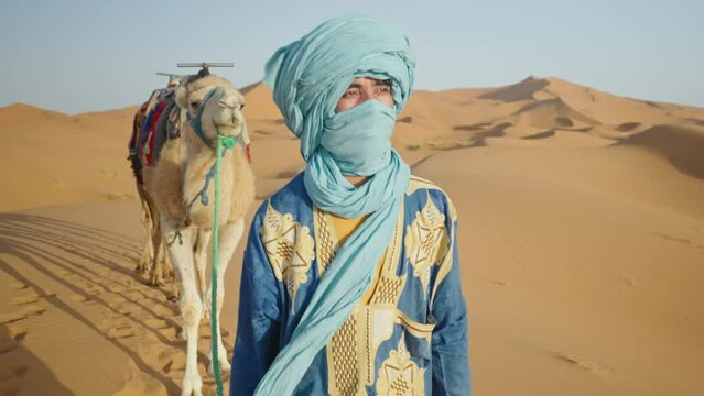 Bedouin with turban and camels walking in the Sahara desert, Merzouga, Morocco
