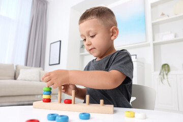 Motor skills development. Little boy playing with stacking and counting game at table indoors