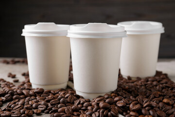 Coffee to go. Paper cups and roasted beans on table, closeup