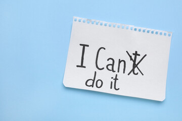 Motivation concept. Changing phrase from I Can't Do It into I Can Do It by crossing out letter T on light blue background, top view. Space for text