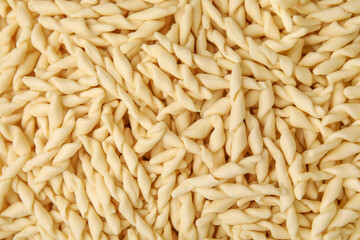 Uncooked trofie pasta as background, top view