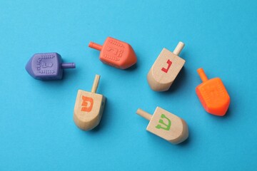 Different dreidels on light blue background, flat lay. Traditional Hanukkah game