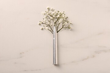 Metal bullet and beautiful gypsophila flowers on light marble table, flat lay