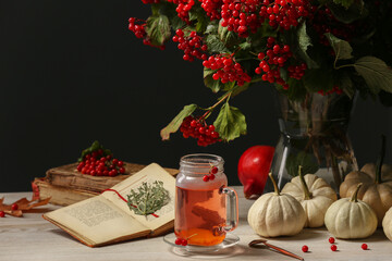 Delicious viburnum tea, books and pumpkins on wooden table, space for text. Cozy autumn atmosphere