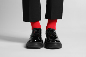 Woman in pants, shoes and stylish red socks on light grey background, closeup