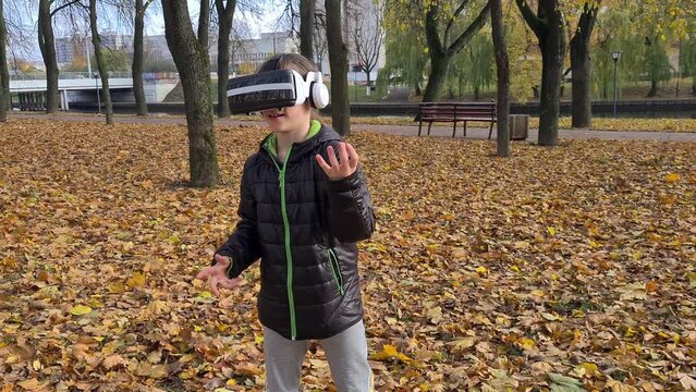 Girl gesturing with VR glasses standing in park. Children virtual games with glasses