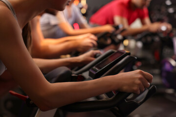 Group of people training on exercise bikes in fitness club, closeup - obrazy, fototapety, plakaty