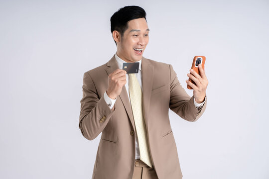 Image of Asian male businessman using phone and holding card credit  on white background