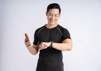 Fototapeta premium Portrait of a man wearing sports clothes, holding a phone and posing on a white background