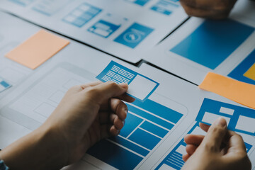Close up ux developer and ui designer brainstorming about mobile app interface wireframe design on...