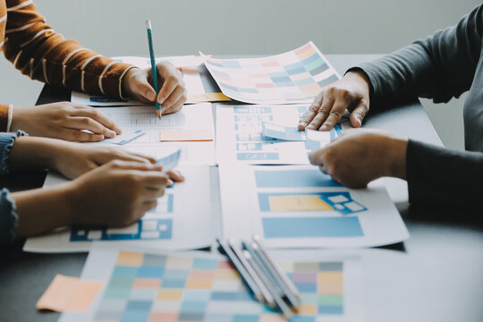 Close up ux developer and ui designer brainstorming about mobile app interface wireframe design on table with customer breif and color code at modern office.Creative digital development agency