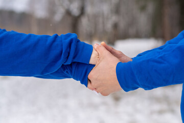 Outdoor happy couple in love posing in cold winter weather. A man and a woman in blue hoodies....