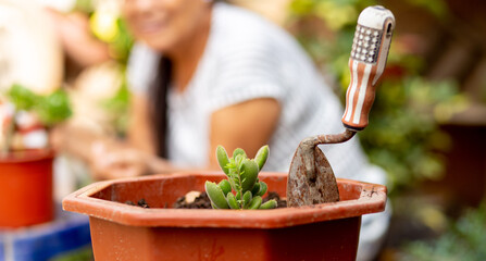 Close-up of a cultivation tool in the foreground, with a blurred background of a smiling woman...