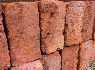 Selective focus. Red bricks from clay. Many clay is molded into bricks, after that it is laid out and dried in the yard in the sun before being burned to make it hard and dry. Pile of making batu bata